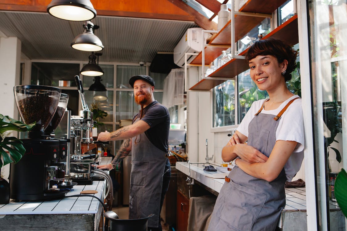 Young man and young woman at coffee machine in cafe