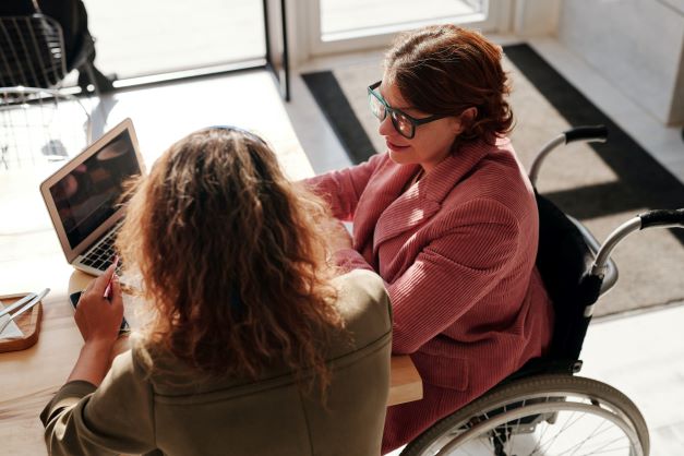 Woman wheelchair user in meeting at table with another woman