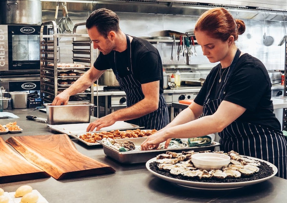 Young man and young woman preparing food in restaurant kitchen